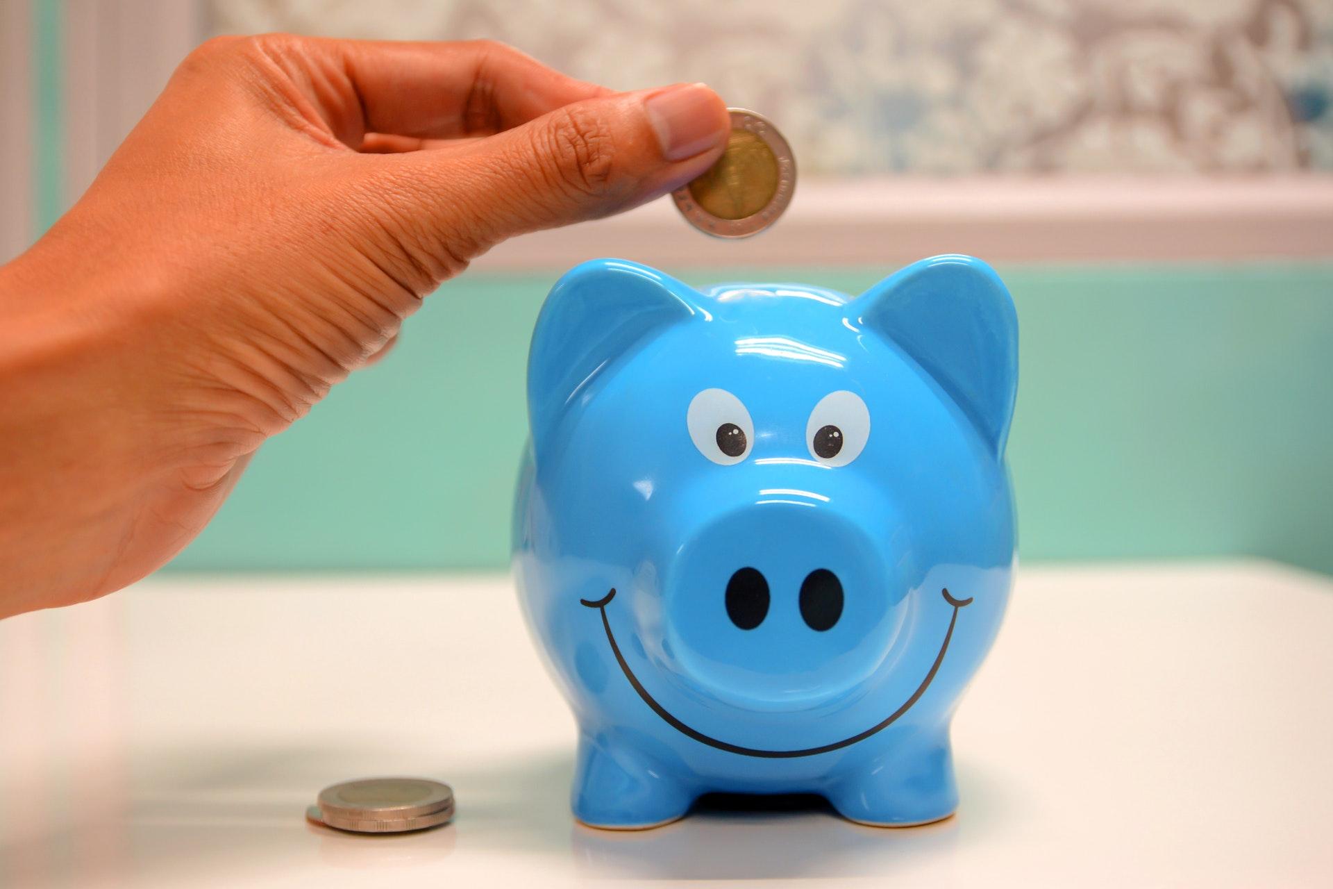 person holding coin in piggy bank