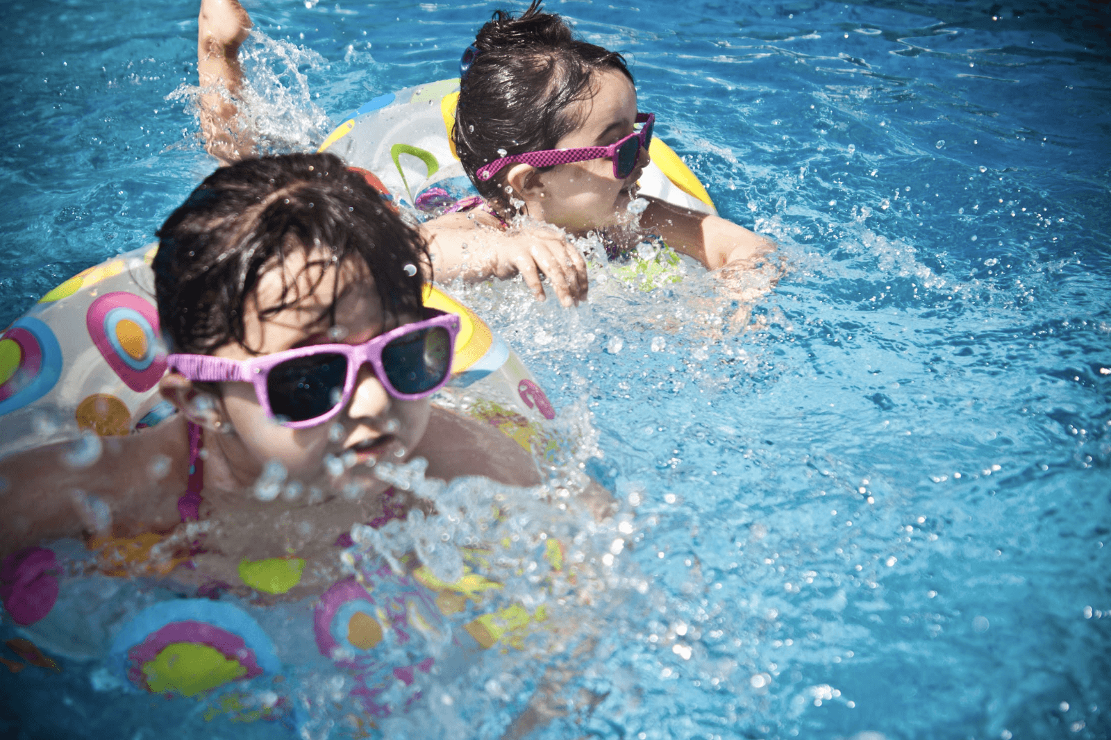 2 girls swimming in pool with floaties