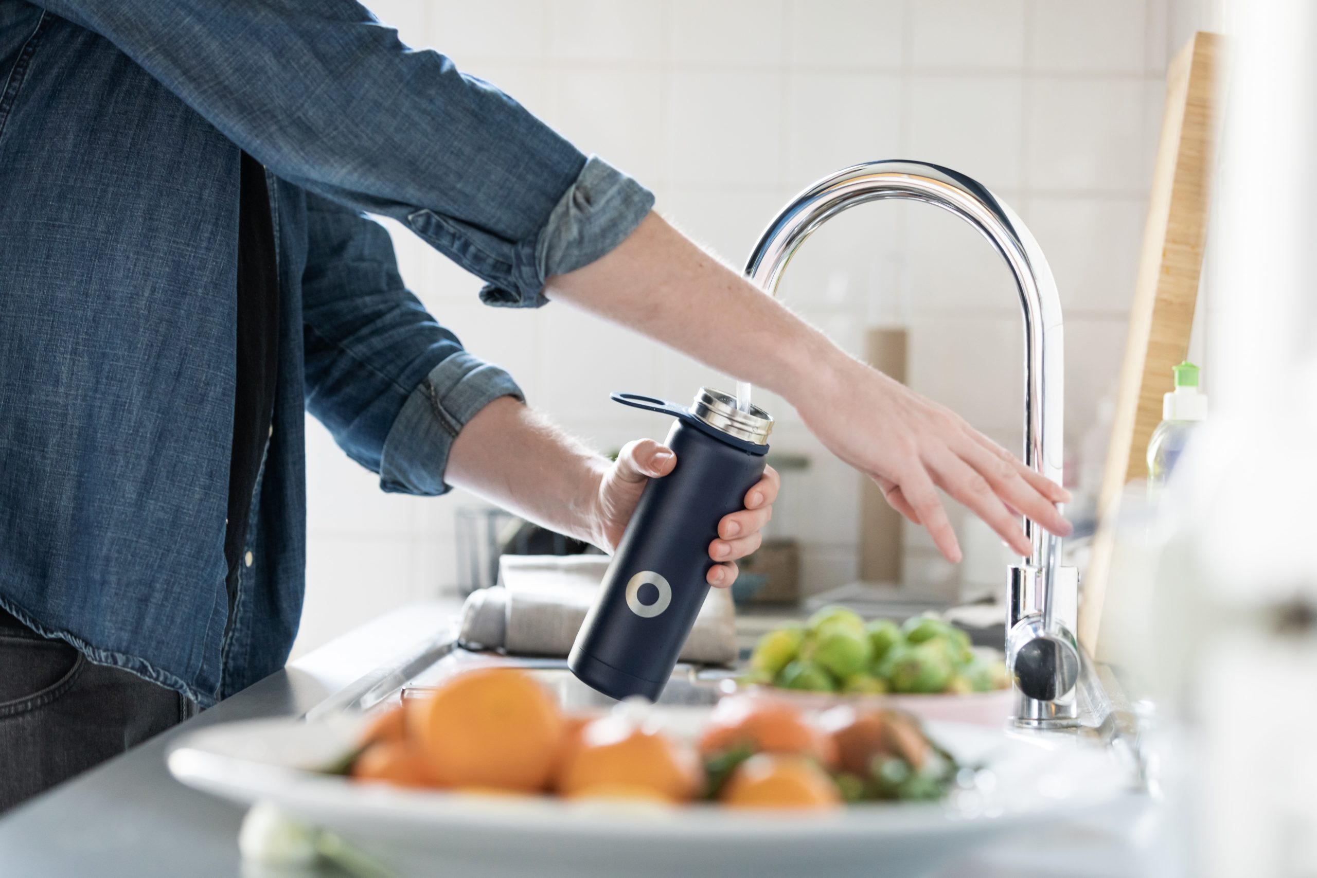 Woman filling water bottle with water from sink